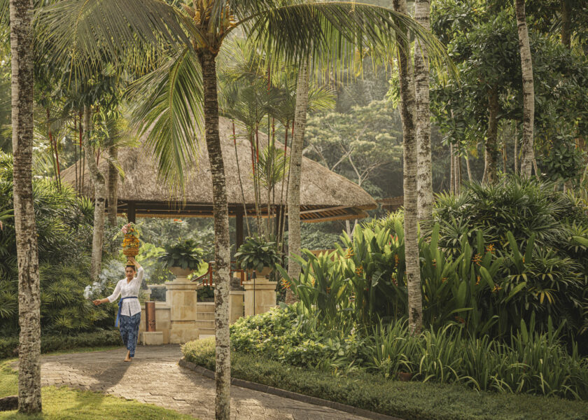 A Balinese woman carrying a ceremonial offering through the tropical gardens of Four Seasons Resort Bali at Sayan, Ubud.
